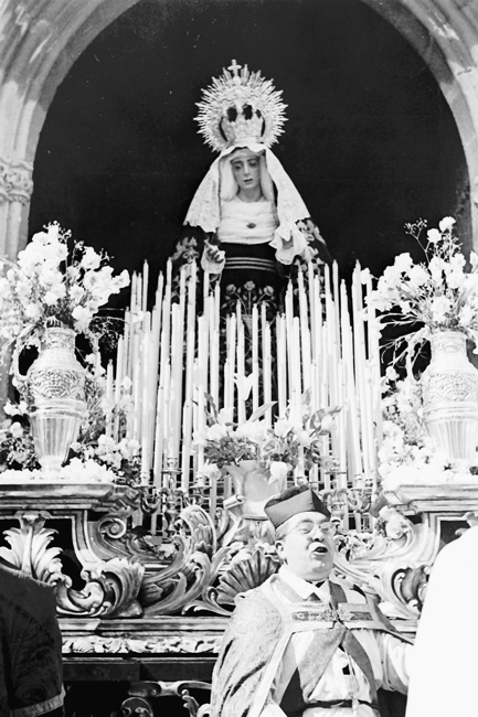 El Jueves Santo de 1960, el Capellán de la cofradía bendice la nueva Imagen de María Stma. de la Caridad a la salida de San Isidoro junto al nuevo trono que la acompaña, todo obra de Francisco Palma Burgos.